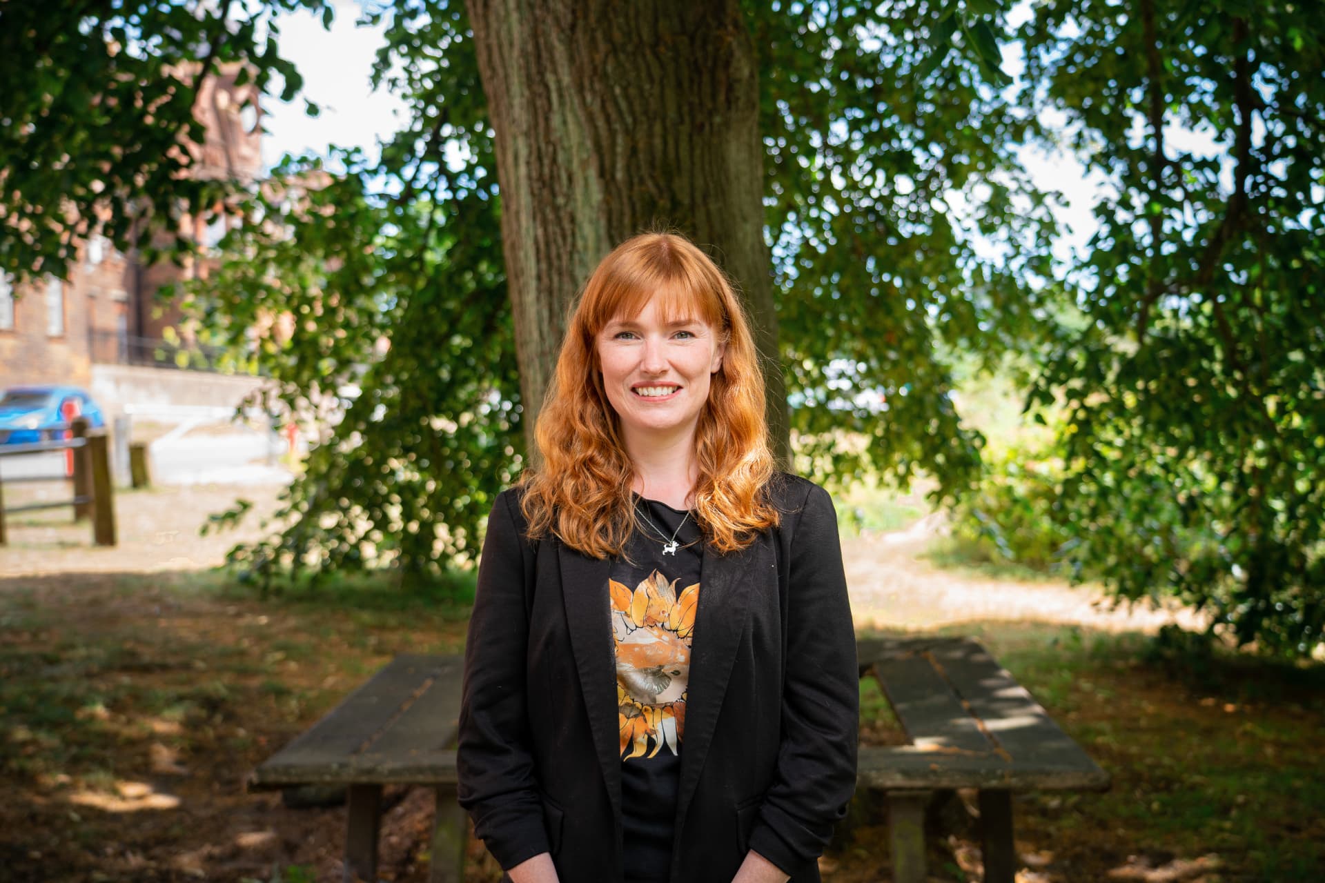 Carly Docking standing outdoors under a tree